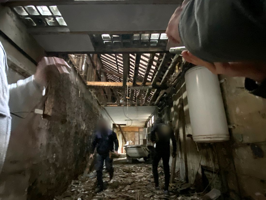 Les combles avant travaux : charpente mise à nu, gravats au sol, deux compagnons au milieu du chantier.