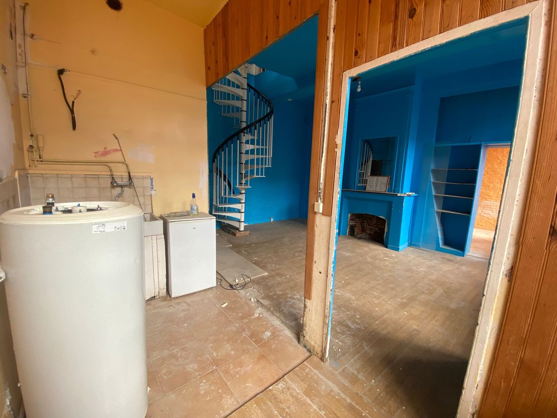 Le duplex avant travaux : murs bleus et lambris, sol nu, escalier en colimaçon d'origine.
